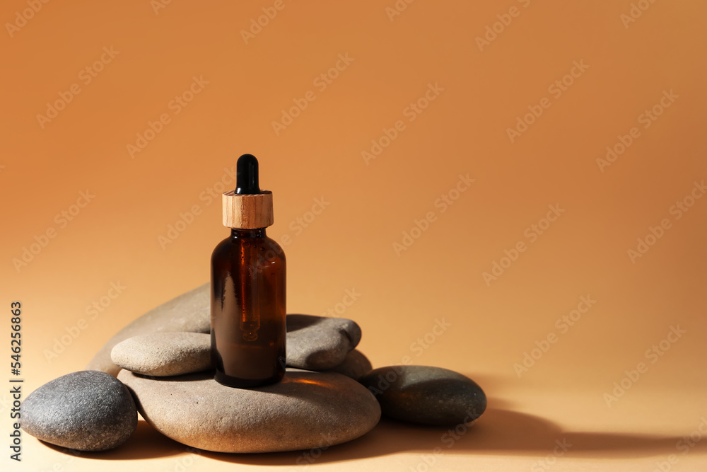 Bottle of face serum and spa stones on beige background, space for text Bottle of face serum and spa stones on beige background, space for text