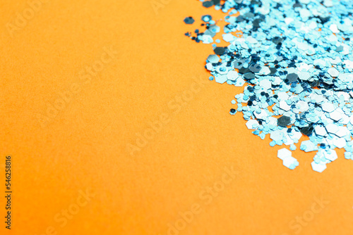 Fototapeta Naklejka Na Ścianę i Meble -  Shiny bright light blue glitter on pale orange background, closeup. Space for text