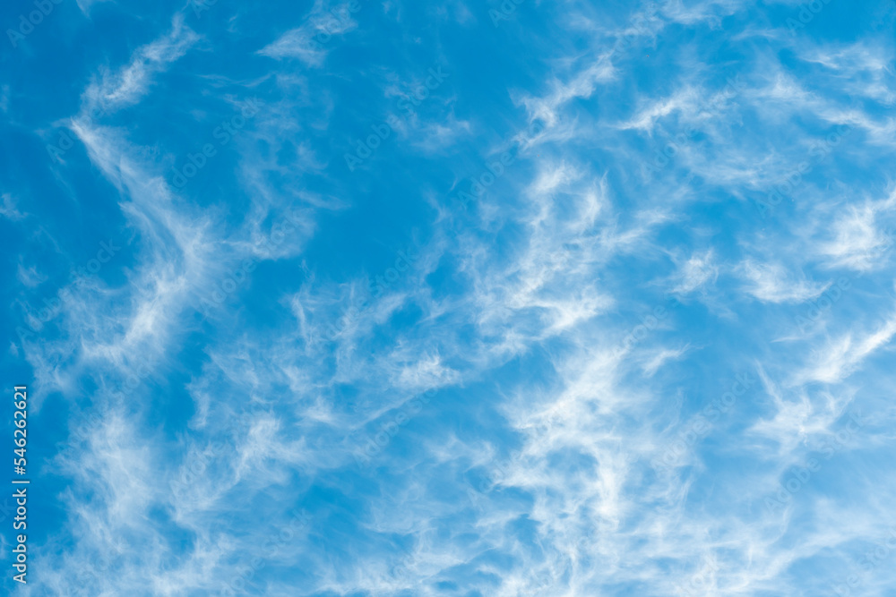 Background with blue sky with high cirrus clouds. Sharp white clouds of irregular, ragged shape.