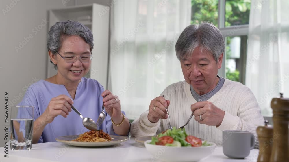 Happy Asian senior couple eating meal together in kitchen at home. Retirement senior couple lifestyle living concept. Happy Asian senior couple eating meal together in kitchen at home. Retirement senior couple lifestyle living concept.