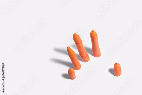Five carrots like the fingers of a hand on a white background.