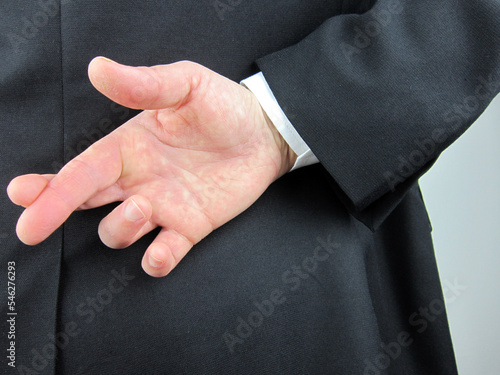 Businessman crossed his fingers behind his back. Good luck or fraud concept.