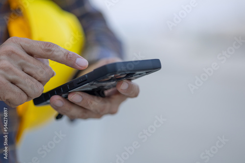 close up construction worker hands touch screen using smartphone