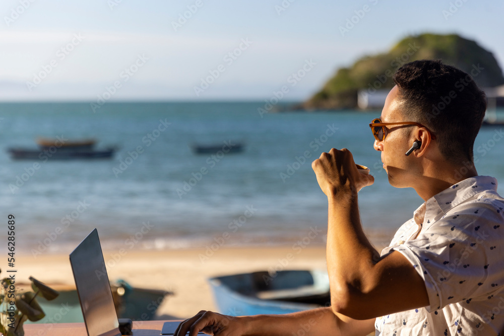 Man using laptop at beach cafe