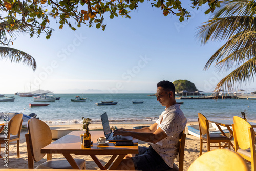 Man using laptop at beach cafe photo