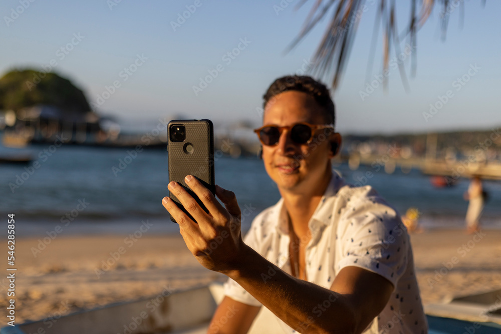 Man sitting at beach and using smart phone