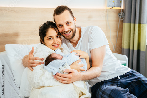 Portrait of happy smiling multiethnic couple with new born baby at hospital ward.