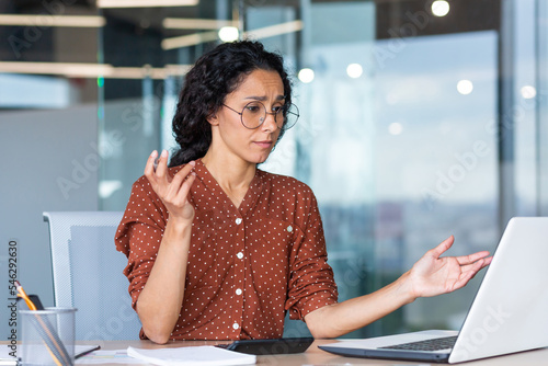 Fotografija Businesswoman disappointed and sad at work, not happy with the result of achievement at work, Hispanic woman desperate and sad working inside office using laptop at work