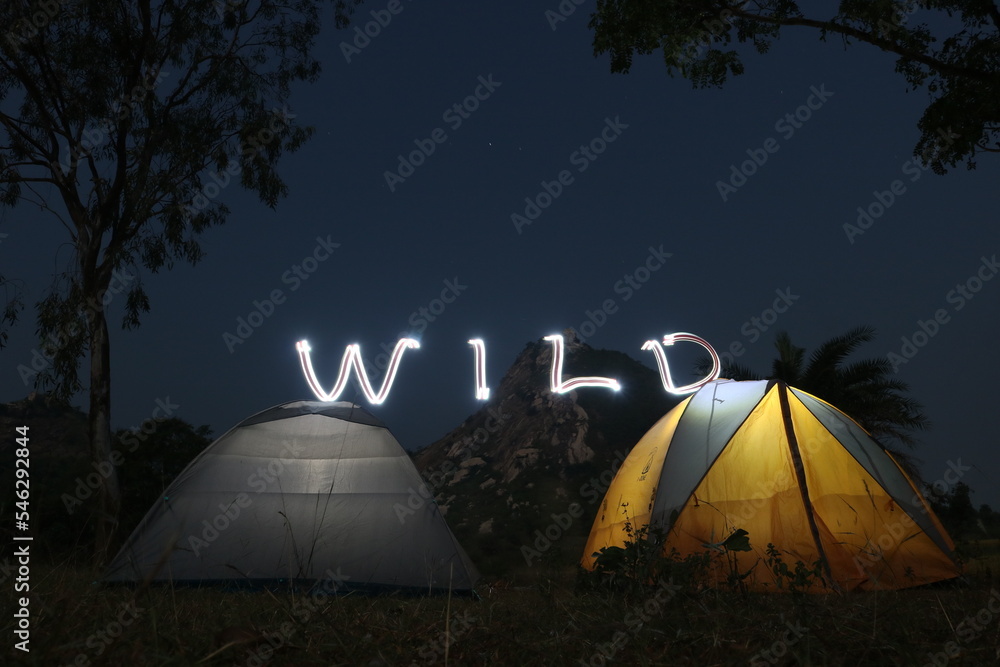 Camping in tent in the wilderness is an amazing adventure. Here two tents are pitched in front of a hill in full moon night.