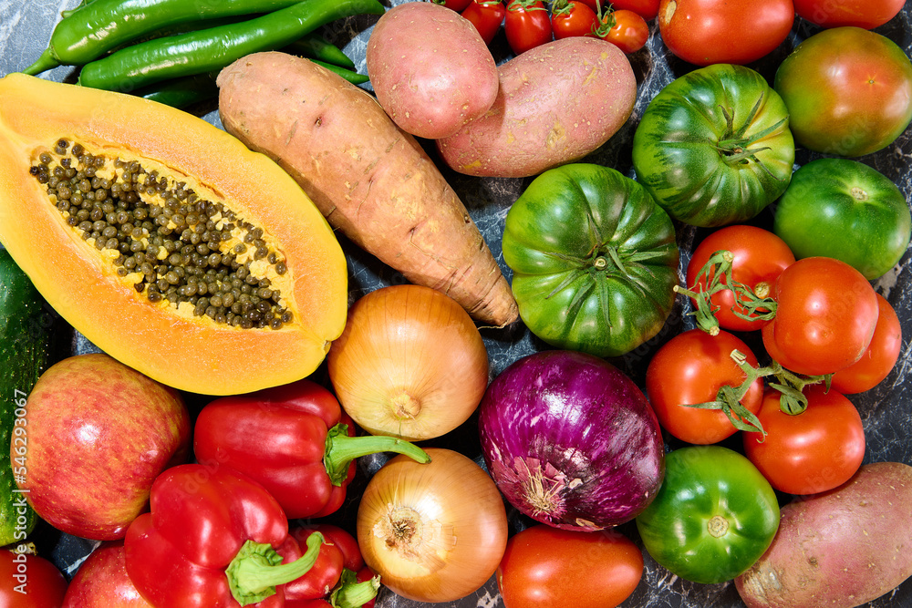 Table with different fresh vegetables and fruits. Papaya, tomatoes, bell peppers, onions and sweet potatoes