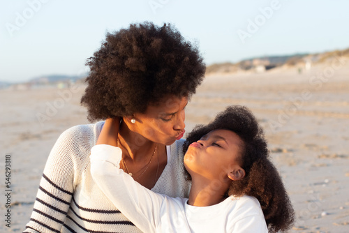 Portrait of happy family on beach. Mother and daughter making faces, hugging, kissing. Family, love, bonding concept
