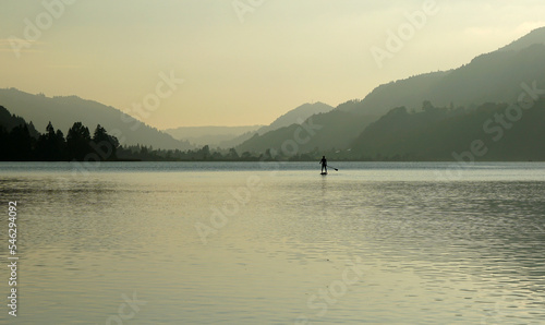 Standup paddling SUP in the afternoon sun at Alpsee, a lake in the German Alps 