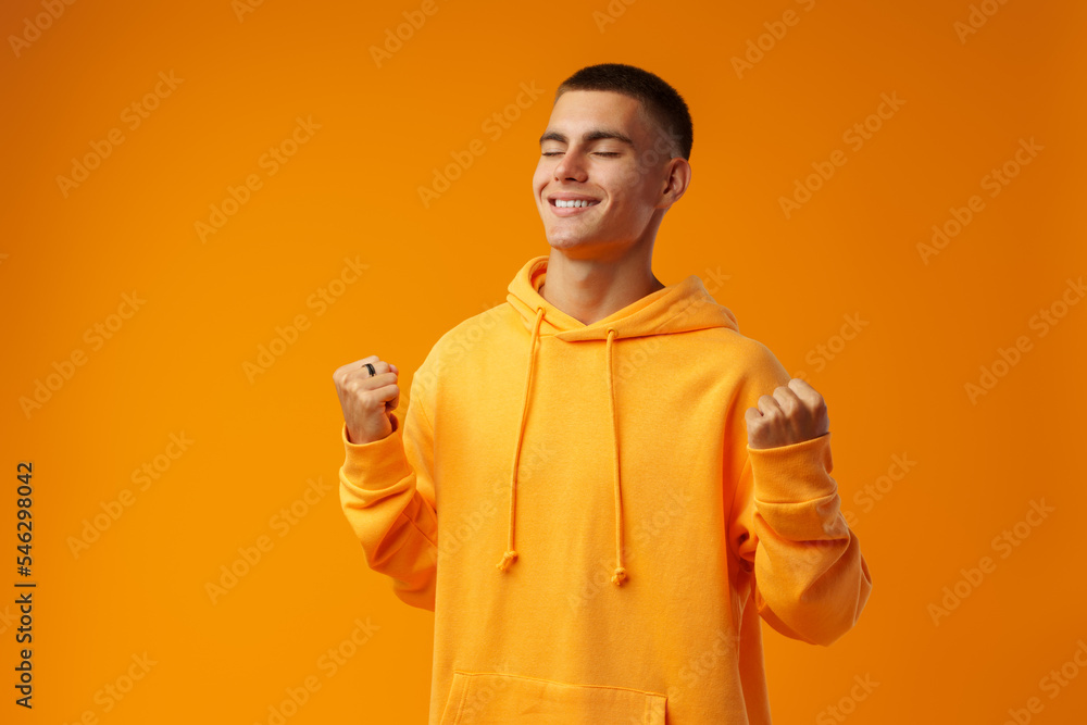 Portrait of a happy young man celebrating success against yellow background Portrait of a happy young man celebrating success against yellow background