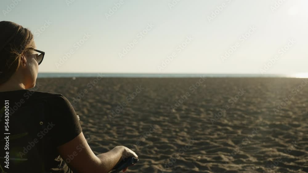 A girl on the beach by the sea sits on a chair near the fire in the grill and looks at the sunset. A girl on the beach by the sea sits on a chair near the fire in the grill and looks at the sunset.