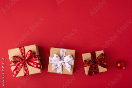 Christmas gift boxes with red balls on red background. © Anna