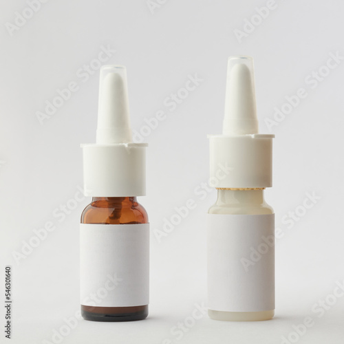 different kind of nasal spray bottles mockup, brown glass and white plastic containers of medical moisturizer for flu and allergies, pharmaceutical aerosol with pump on a gray background, blank label photo