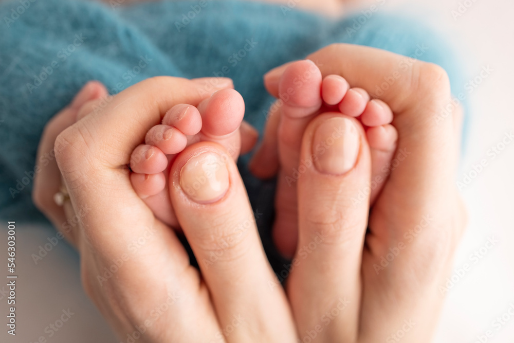 Mother is doing massage on her baby foot. Close up baby feet in mother hands on a blue background. Prevention of flat feet, development, muscle tone, dysplasia. Family, love, care, and health concept Mother is doing massage on her baby foot. Close up baby feet in mother hands on a blue background. Prevention of flat feet, development, muscle tone, dysplasia. Family, love, care, and health concept