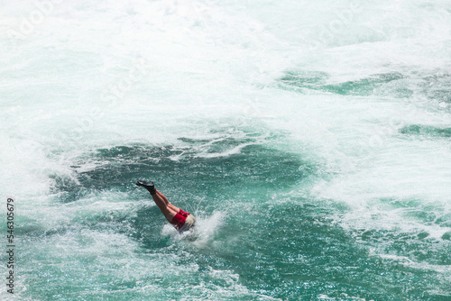 young man jump into the water of the clean river on the waterfall, swims, enjoys spending time on summer holidays. 