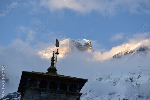 Low angle of the Kedarnath temple with the Garhwal Himalayas snow peaks in clouds in the background photo