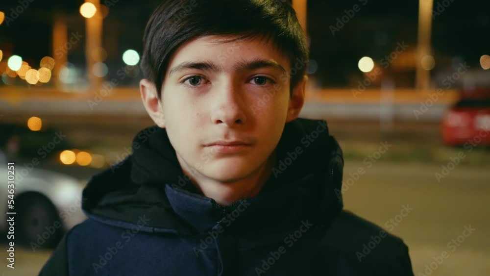 Lonely sad boy standing in street in night dark city with passed by cars. Problems of parenting. Concept of solving psychological factors Lonely sad boy standing in street in night dark city with passed by cars. Problems of parenting. Concept of solving psychological factors