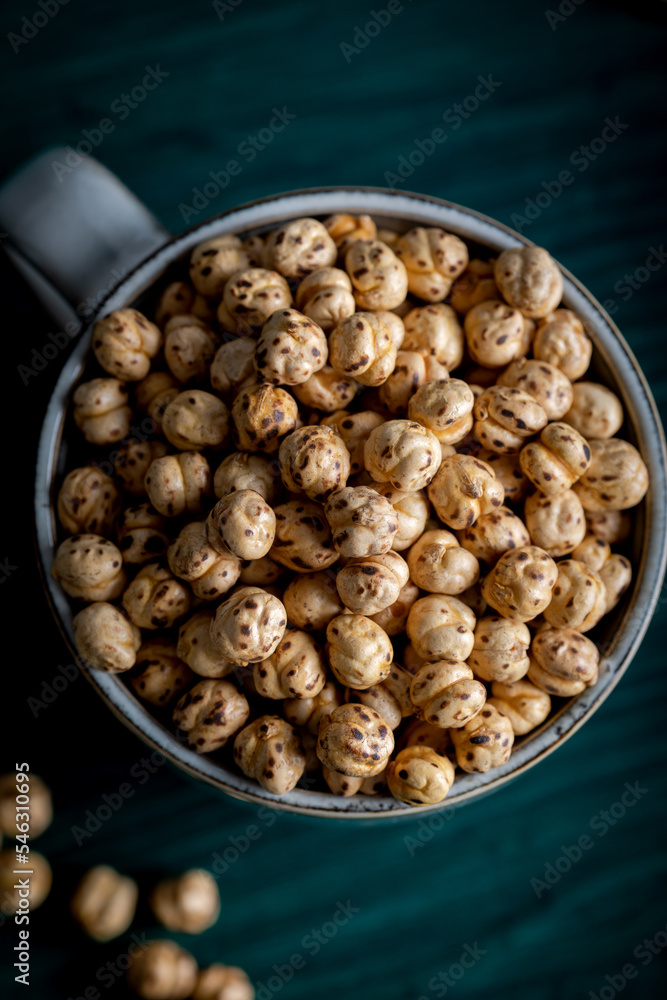 Roasted spicy chickpeas. Roasted chickpeas in a porcelain cup on wooden white background