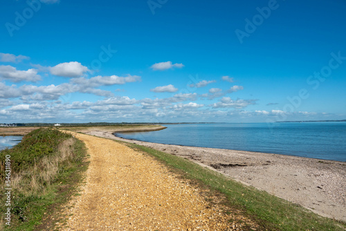 footpath along the Solent Way between Lymington and Keyhaven with the sea blue sky and wispy white clouds photo