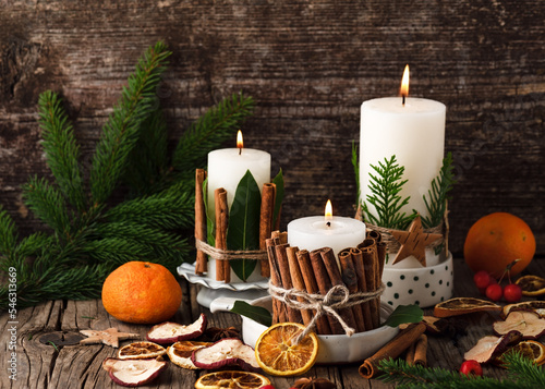 Burning Christmas or advent candles decorated with natural material. Slices of fresh dried apple, orange and spices for cooking or baking. Rustic style. © Oksana Schmidt
