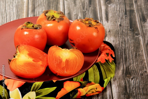 Fresh persimmon fruit on plate. Persimmon fruit Old board background