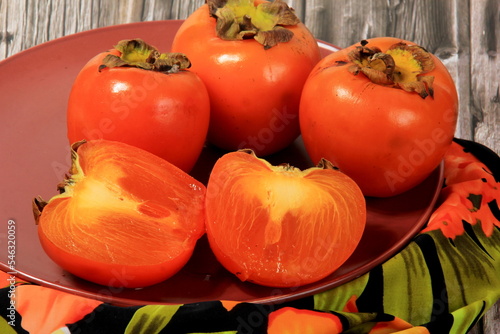 Fresh persimmon fruit on plate. Persimmon fruit Old board background photo