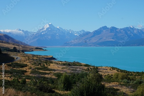 Low-angle of a landscape with a seascape and beach with grass Aoraki Mount Cook background