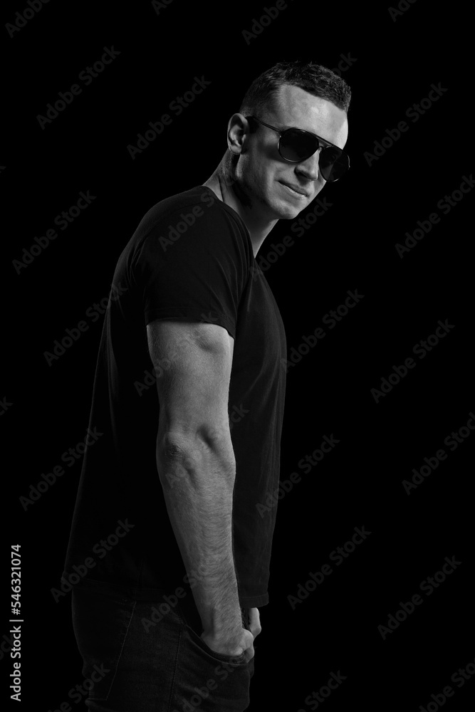 Black and white portrait of brutal handsome young man posing in sunglasses over black background. Concept of fashion and lifestyle Black and white portrait of brutal handsome young man posing in sunglasses over black background. Concept of fashion and lifestyle
