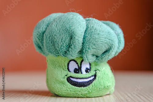 Soft plush toy for children - green broccoli. Broccoli with a happy face. Children's toy close-up, space for text.