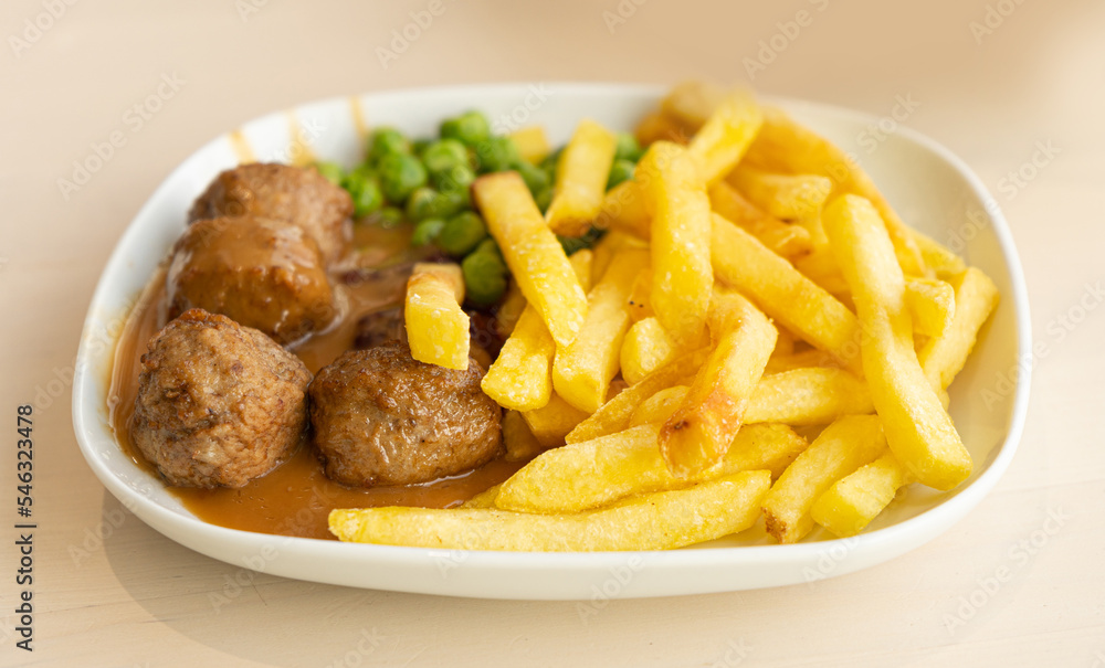 Meatballs with French Fries, Green Peas, Bechamel Sauce, Meat Balls on White Plate Closeup Meatballs with French Fries, Green Peas, Bechamel Sauce, Meat Balls on White Plate Closeup