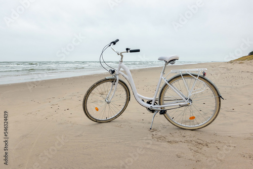 White bike on the sand by the Baltic sea. Bicycle on the sandy shore, nobody.