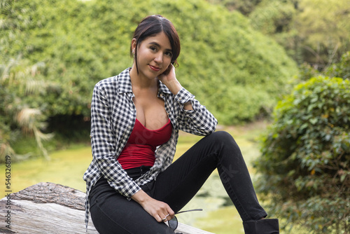 beautiful woman with natural beauty and collected hair smiling and resting sitting, in the background landscape with nature at daytime, lifestyle photo