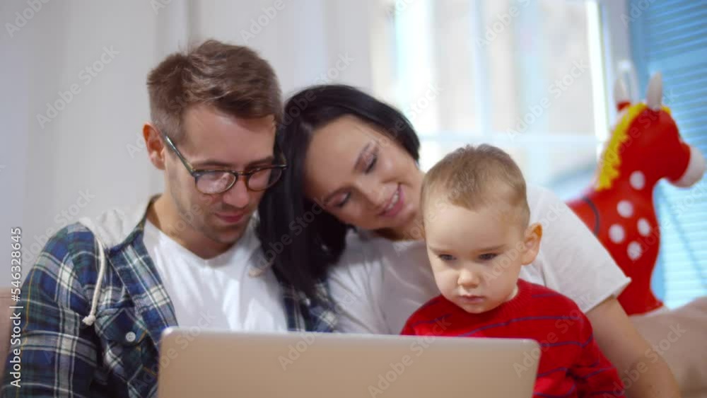 Portrait of caucasian family use laptop sitting on couch with baby at home. Realtime Portrait of caucasian family use laptop sitting on couch with baby at home. Realtime