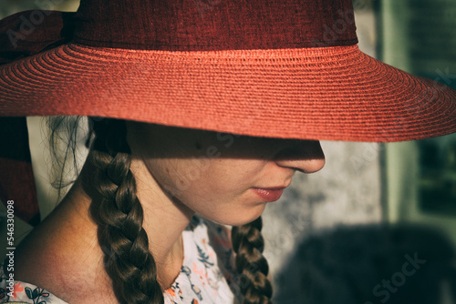 A girl wearing a big sun hat covering her face