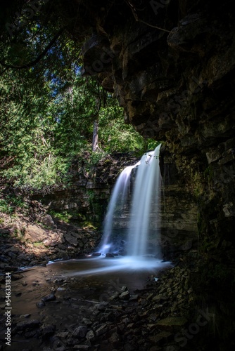 Vertical long exposure view of waterfall surrounded by rocks and trees