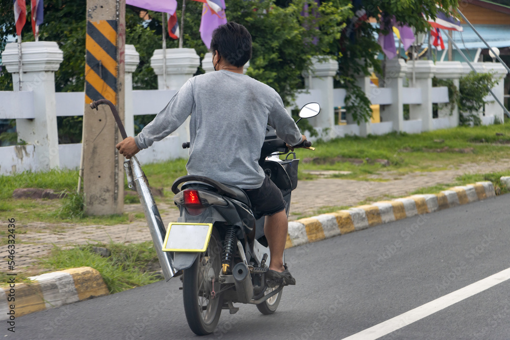 Obraz premium A man rides a motorcycle and holds a motorcycle exhaust in one hand, Thailand