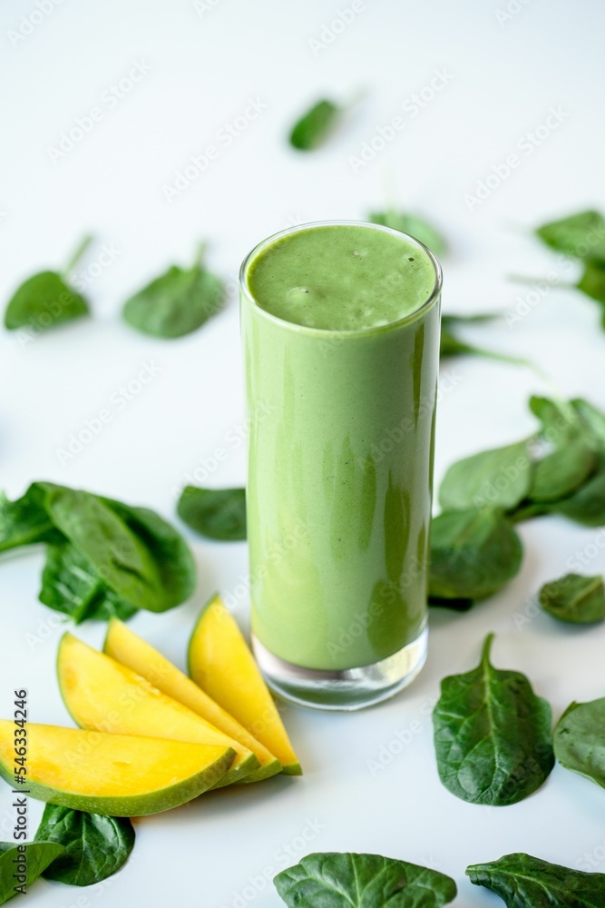 Vertical shot of a green healthy milkshake in a glass mug on white surface Vertical shot of a green healthy milkshake in a glass mug on white surface