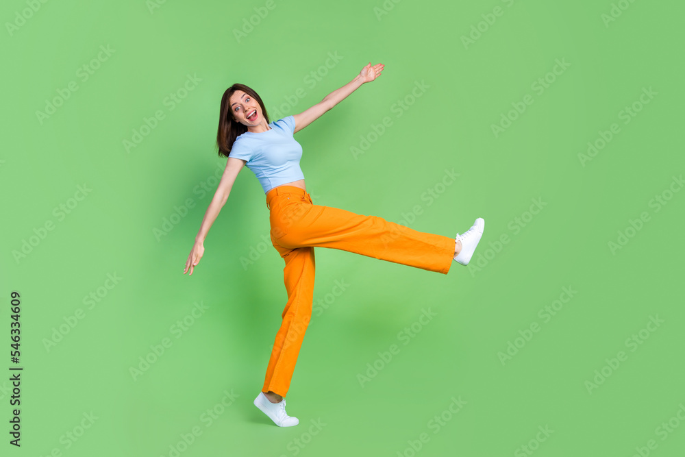 Full body profile photo of satisfied glad lady make big step good mood isolated on green color background Full body profile photo of satisfied glad lady make big step good mood isolated on green color background