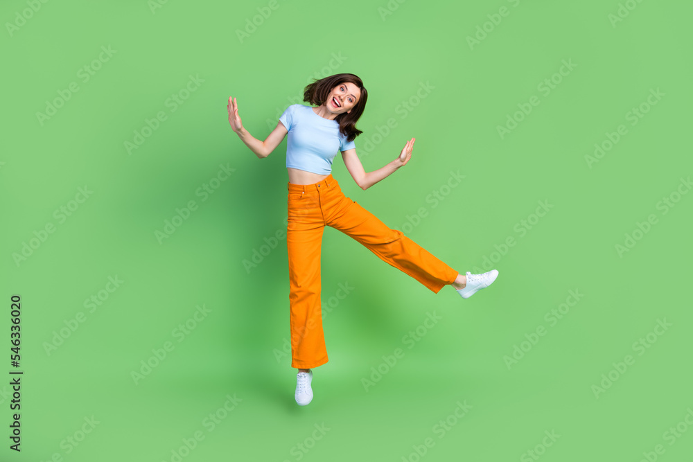 Full length photo of cheerful gorgeous person jumping have good mood isolated on green color background