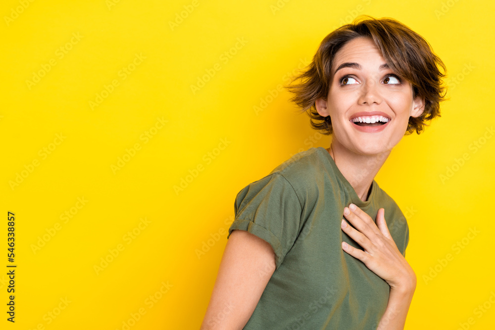 Photo of cheerful ecstatic girl with bob hairstyle wear khaki t-shirt look empty space hand on chest isolated on yellow color background Photo of cheerful ecstatic girl with bob hairstyle wear khaki t-shirt look empty space hand on chest isolated on yellow color background