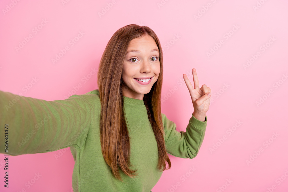 Photo of adorable funny optimistic girl with straight hairstyle wear green sweater showing v-sign isolated on pink color background Photo of adorable funny optimistic girl with straight hairstyle wear green sweater showing v-sign isolated on pink color background