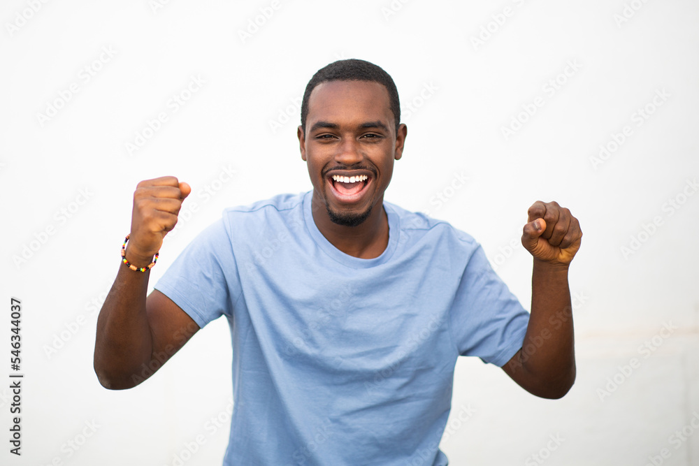 Fototapeta premium Excited young african man with arms raised against white background
