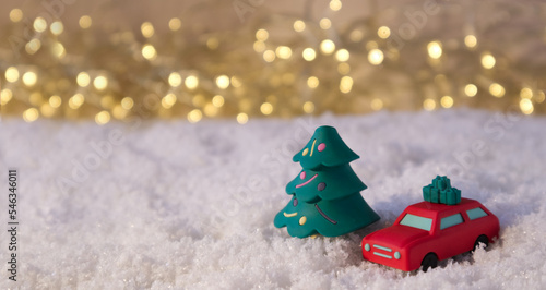 Red car and the Christmas tree in the snow against the background of lights photo