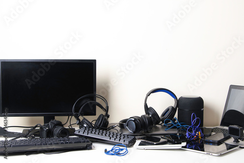 Old computers, digital tablets, mobile phones, headphones, many used electronic gadgets devices on white table. E-waste, planned obsolescence, electronic waste for reuse, refurbish and recycle concept