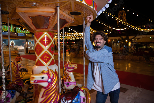 A smiling boy leans on a carousel at the sideshows during christmas.