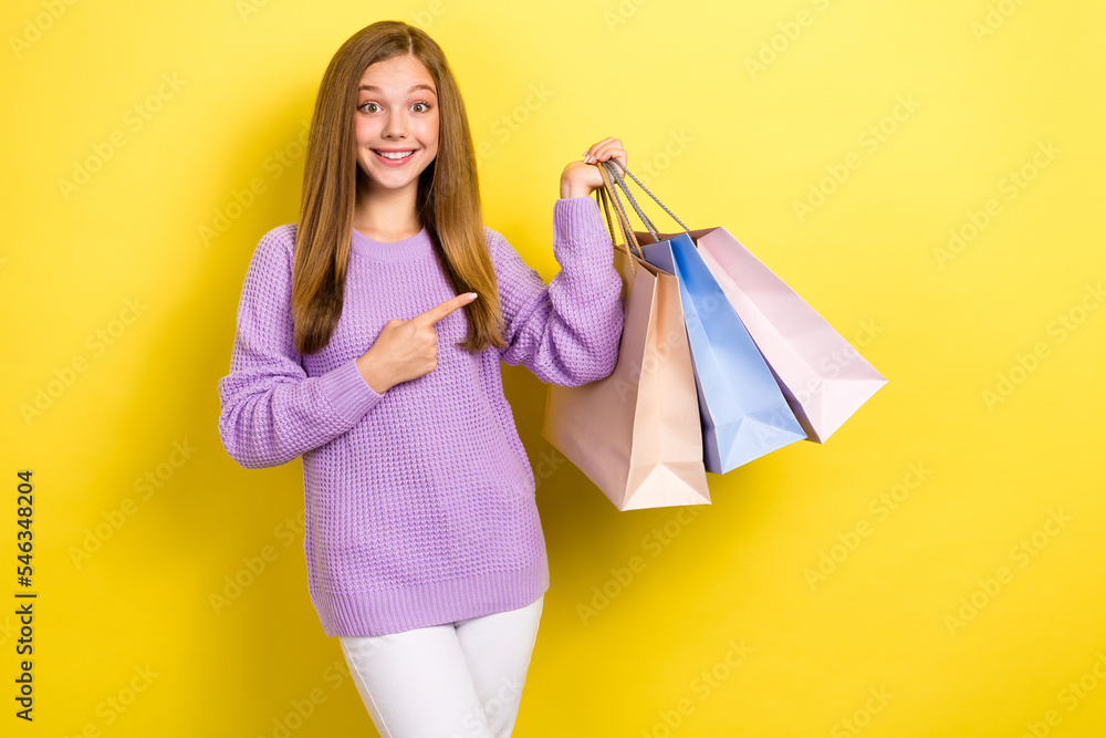 Photo of young schoolgirl teenager shopaholic excited wear stylish outfit sale clothes finger directing stack bags new brand isolated on yellow color background