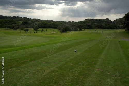 Flag on a golf coarse at the putting hole with lush green turf, taken on a clouded murky day with soft lighting, hole in one